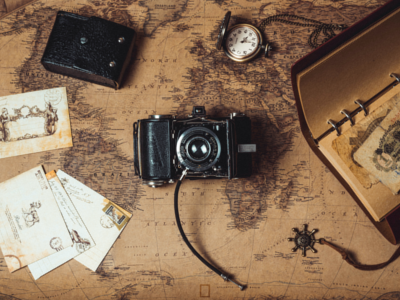 photo of a camera and a watch with papers on top of a map
